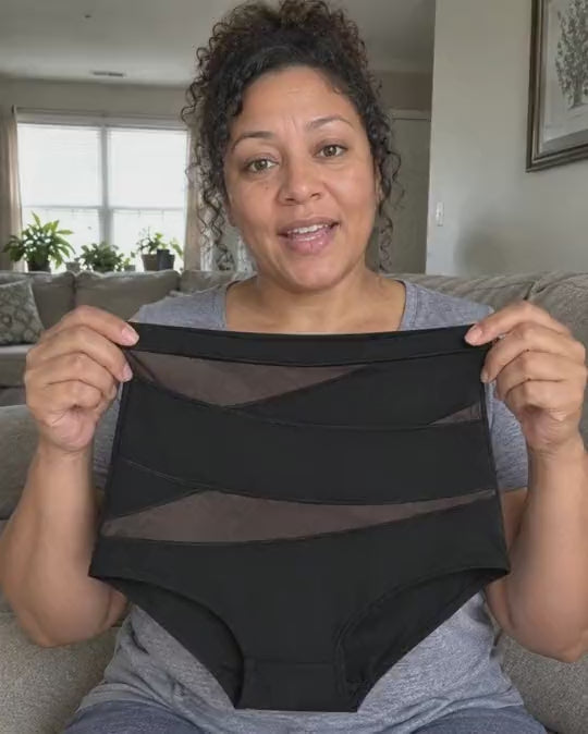 Femme assise sur un canapé qui tient une culotte taille haute